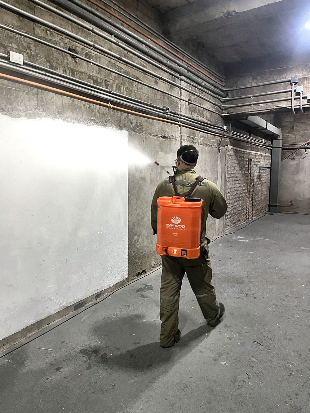 Técnico de EXTERMINIO aplicando con pulverizadora inalámbrica en un subterráneo